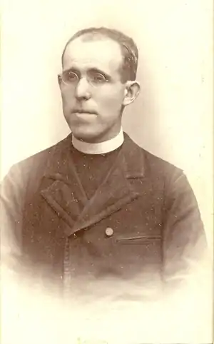 Photo noir et blanc d'un prêtre en clergyman, avec un visage en longueur, portant lunettes.