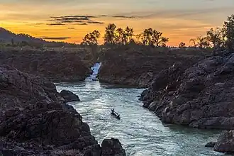 Cascades de Li Phi (chutes de Khone) au crépuscule avec un ciel jaune orangé.