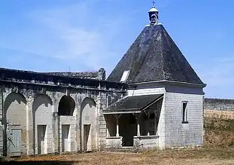 Photographie en couleurs d'un petit bâtiment carré coiffé en pyramide.