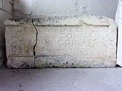 Photographie en couleurs d'une pierre taillée gravée d'inscriptions.