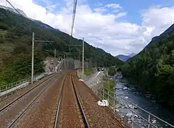 Photographie de la ligne ferroviaire à Orelle en 2020 avec les deux voies rouillées et l'Arc à côté.