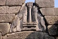 Détail du bas-relief de la porte des Lionnes : Deux lions rampants se faisant face de part et d'autre d'une colonne, les pattes avant posées sur deux autels biconcaves.