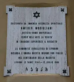 Photo en couleur d'une plaque carrée claire sur un mur avec des caractères noirs