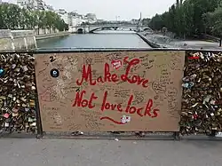 Section de rambarde remplacée, par mesure de prévention, par un panneau contreplaqué ultérieurement graffité d'un slogan anti-cadenas.