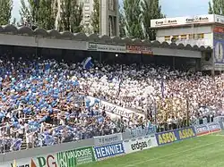 Photographie en couleur d’une tribune d’un stade de football remplie de supporters