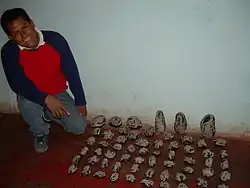 Photographie d'un homme accroupi à côté de plusieurs rangées de pierres noires ornées de gravures blanches.