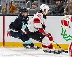 Deux joueurs de hockey en action dont un porte le numéro 43, l'autre le numéro 7.