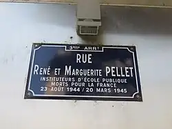 Photo de la plaque sur laquelle est écrit, en blanc sur fond bleu marine : "Rue René et Marguerite PELLET, instituteurs d'école publique morts pour la France - 23 août 1944 / 20 mars 1945".