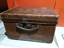 Photo en couleur d'une grosse mallette de cuir sombre avec des éraflures