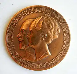 Le couple royal, de profil, regardant vers la gauche, la reine au premier plan droit, le prince au second plan gauche. Sur le pourtour, l'inscription : KONINGIN WILHELMINA - HENDRICK PRINS DER NEDERLANDEN.