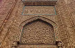 L'arc brisé surmontant l'entrée, avec son décor géométrique dans le tympan, et la calligraphie qui le surmonte.