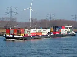 porte-conteneurs sur un canal devant une éolienne.