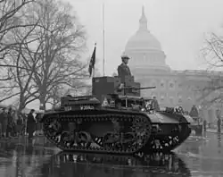 Véhicule à chenille défilant devant le Capitole de Washington sous la pluie.