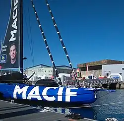 Vu de profil, avant d'un voilier bleu amarré au ponton.