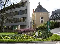 Photographie présentant le bâtiment de la mairie : à gauche, la partie moderne, sur pieux, raccordée à un bâtiment carré au centre par une passerelle vitrée, à droite la structure métallique qui abrite le cloitre d'eau.