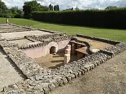 Photographie des vestiges de pièces antiques avec au premier des empilements de briques pour surélever un plancher disparu.