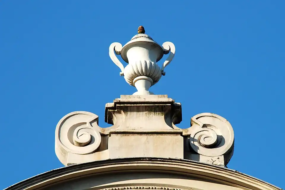 Le pinacle à volutes portant un vase de pierre.