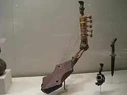 Harpe cintrée à 5 cordes ornée d'une figure anthropomorphe.