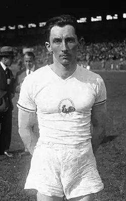 Photographie en noir et blanc représentant le portrait d'un homme en T-Shirt et un short blancs.