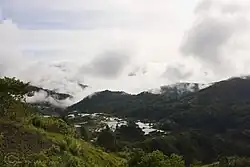 Des rizières en terrasse avec de petits bâtiments dans un paysage de montagnes très vertes.