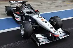 Photo d'une monoplace noire et argentée dans une voie des stands