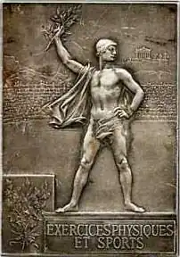 Médaille rectangulaire représentant un athlète sur un podium brandissant une branche de laurier avec à l'arrière-plan l'acropole d'Athènes