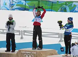 Vue de loin de trois femmes sur le podium, la première levant les bras en l'air.