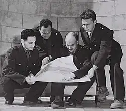 Photographie en noir et blanc d'un groupe de 4 hommes en uniforme.