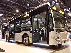 Photographie en couleurs d’un autobus gris exposé sur un salon.