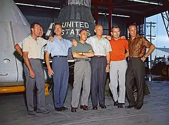 Sept hommes posant devant un engin spatial.