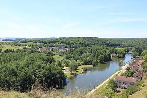 Une rivière traversant un paysage de forêts vallonné, d'où sort un village.