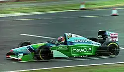 Vue de côté d'une monoplace bleue et verte en piste