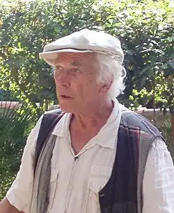 Homme avec casquette et cheveux blancs dans un parc.