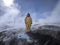 Personne en habit de protection jaune près d'échantillons sur un volcan.