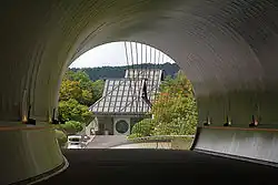 Bâtiment de forme traditionnelle des maisons japonaises dans un lieu de verdure mais avec verre et structure en métal.