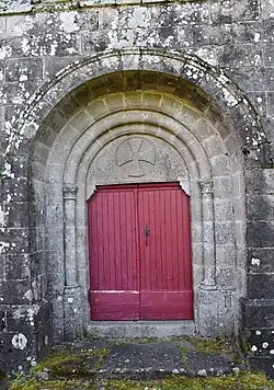 Le portail roman surmonté d'une croix de Malte.