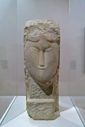 Photo couleur d'une tête de femme ovale émergeant d'un bloc de pierre