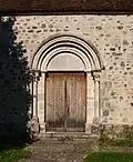 Portail roman avec archivoltes en dents de scie et des colonnettes à chapiteaux.