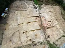 Photographie aérienne en couleurs de terrains décapés avec des vestiges de murs