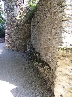 Photographie en couleurs des vestiges d'un mur à la base d'une tour.