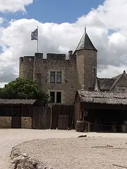 Photographie en couleurs d'un ensemble de bâtiments dont une tour cylindrique à l'aspect médiéval.