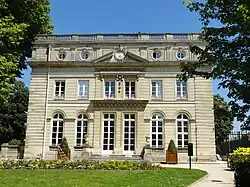 Bâtiment ancien en pierre blanche, de trois étages, avec un fronton triangulaire et un toit-terrasse.