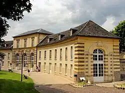 long bâtiment incurvé en pierre, au toit d'ardoise.