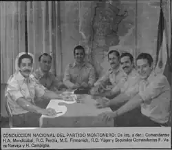 six hommes bruns souriants autour d'une table rectangulaire.