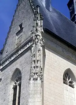 Vue d'un contrefort d'église surmonté d'une décoration de volutes.