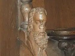 Tête sculptée sur l'accoudoir en bois séparant deux stalles.