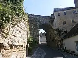 Photographie en couleurs d'une arche en pierre enjambant une rue encaissée