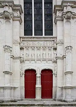 Vue de la façade d'une église, de son portail à deux battants et de la verrière qui le surmonte.