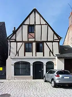 Photographie en couleurs d'une maison dont la partie supérieure du pignon est faite de colombages.