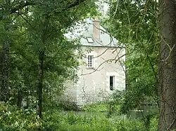Photographie en couleurs d'un édifice carré surmonté d'une toiture pyramidale établi sur un cours d'eau.